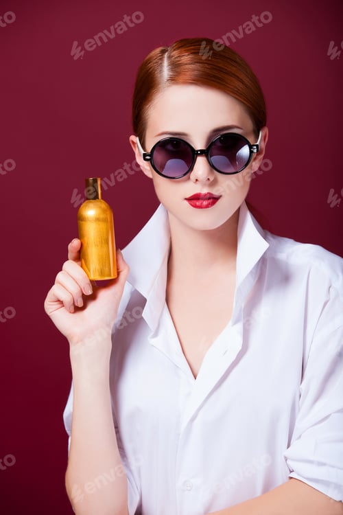 Preview: Redhead in sunglasses with perfume on red background