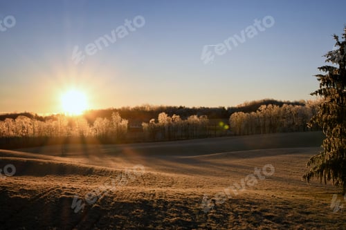 Preview: Early morning sun sunrise over a frozen winter landscape.