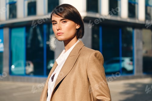 Preview: Young beautiful stylish businesswoman confidently looking in camera on street