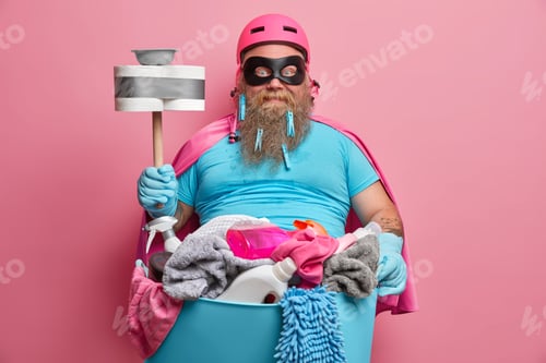 Preview: Ready to work and tidy up everything. Superhero with thick beard ready for cleaning day holds plunge