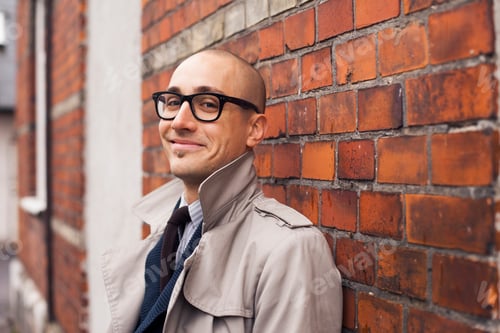 Preview: Portrait of smiling man leaning on brick wall