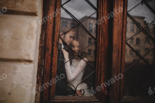 Preview: Young stylish newlyweds are hugging behind old rustic wooden door. wedding day.