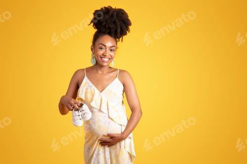 Vista previa: Alegre mujer embarazada negra milenaria tocando una gran barriga, disfruta del embarazo, muestra zapatos pequeños