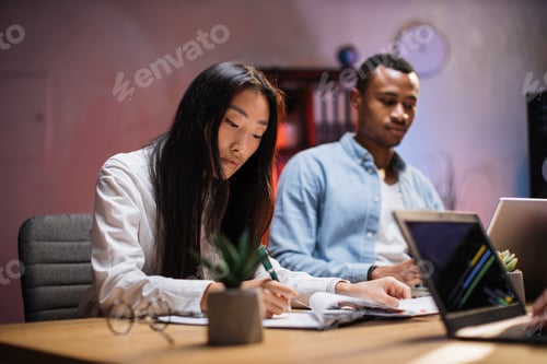 Preview: Diverse brokers with gadegts analyzing charts at office