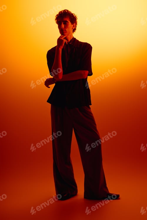 Preview: Stylish young man showcases modern fashion against a warm gradient backdrop