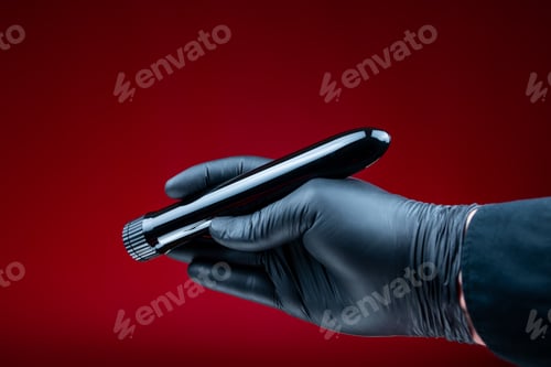 Preview: hands in black gloves holding a bullet-shaped vibrator in black for bdsm games