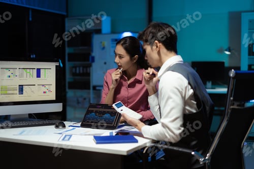 Preview: Financial analysts work overtime analyzing data on tablets, laptops, and graphs.