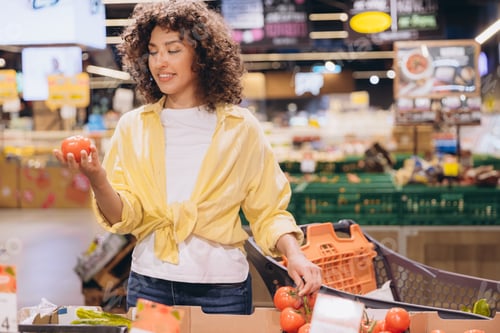 Preview: Woman choosing tomatoes in supermarket aisle