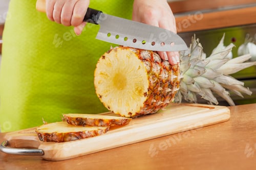 Preview: Woman chopping fresh pineapple on cutting board...
