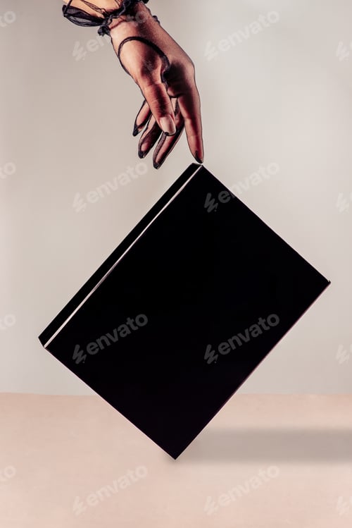 Preview: Box or book cover on the beige background with hand in vintage gloves