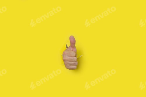 Preview: Hand with thumb up as a sign of approval, coming out of the hole of a yellow torn paper background.
