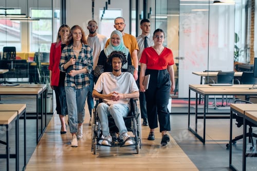 Preview: A diverse group of young business people congregates within a modern startup's glass-enclosed office
