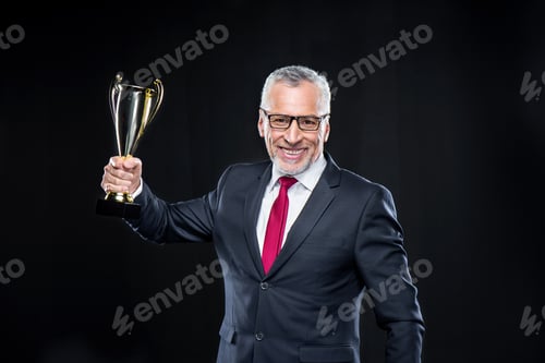 Preview: Happy mature businessman holding award cup isolated on black