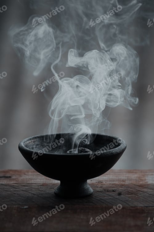 Preview: Vertical shot of a burning incense in a black bowl