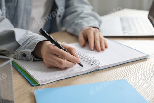 Preview: Woman taking notes at wooden table indoors, closeup. Self-study