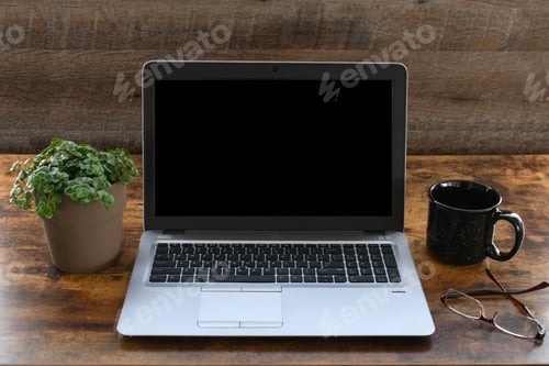 Preview: Laptop computer on a desk in dark wood office with black blank screen for mock up.