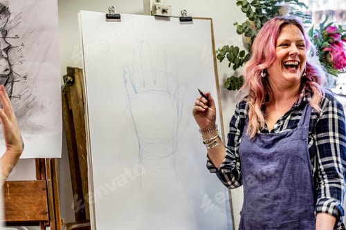 Preview: Laughing woman wearing apron standing at an easel, drawing of human hand.