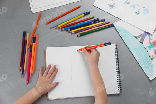 Preview: Little boy drawing with pencil at grey textured table, top view. Child`s art