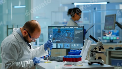 Preview: Man scientist using micropipette for filling test tubes in modern equipped laboratory