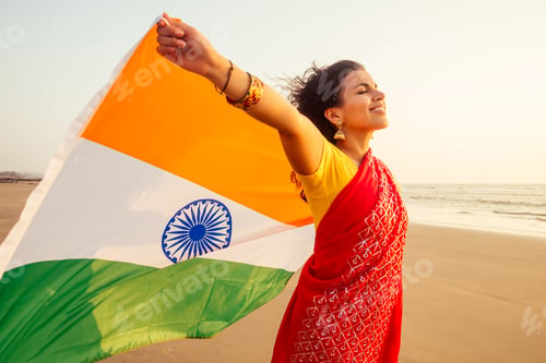 Preview: beautuful woman holding Indian flag tricolour ,wearing red tradition sari on sea beach in Goa
