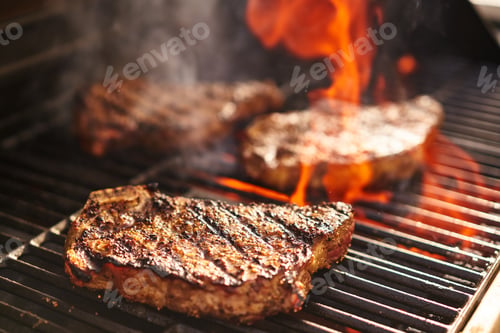 Preview: steaks cooking over flaming grill