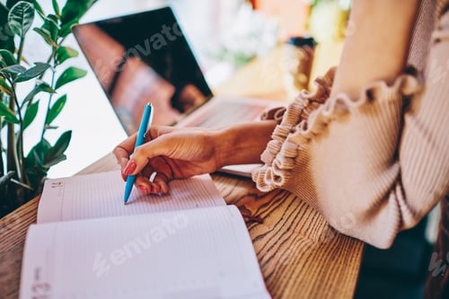 Preview: Faceless freelancer writing notes in cafe