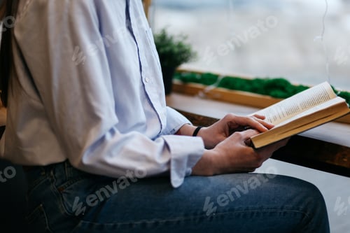 Vista previa: brunette girl in a cafe drinking coffee, reading a book