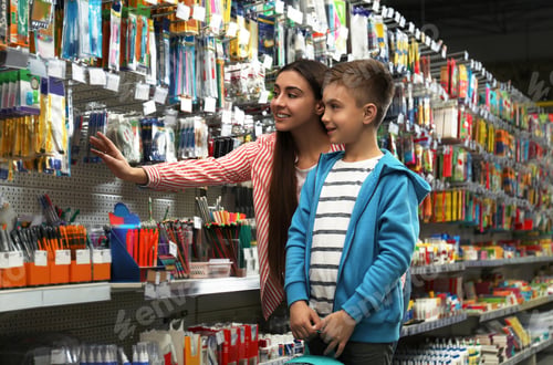 Preview: Little boy with mother choosing school stationery in supermarket