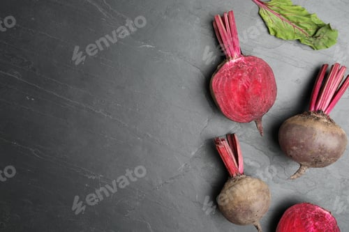Preview: Cut and whole raw beets on grey table, flat lay. Space for text