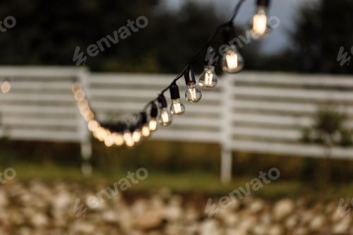 Preview: Beautiful night yellow light bulbs on the street. Light Bulb hanging at the dark summer night with