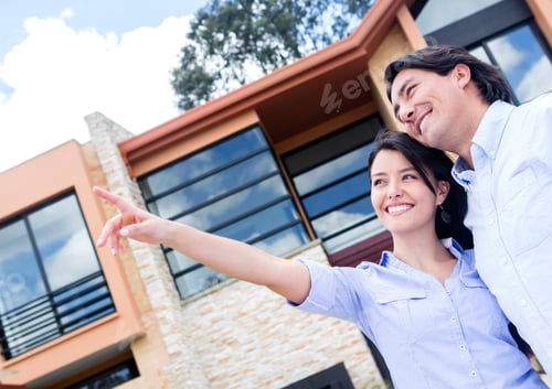 Preview: Happy Couple Pointing Away In Front Of Their Home