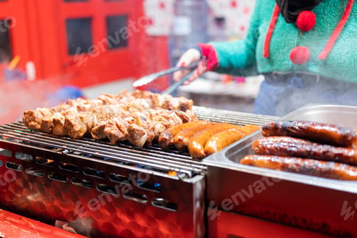 Preview: vendor fries meat and sausage on the grill in the city center at the Christmas market