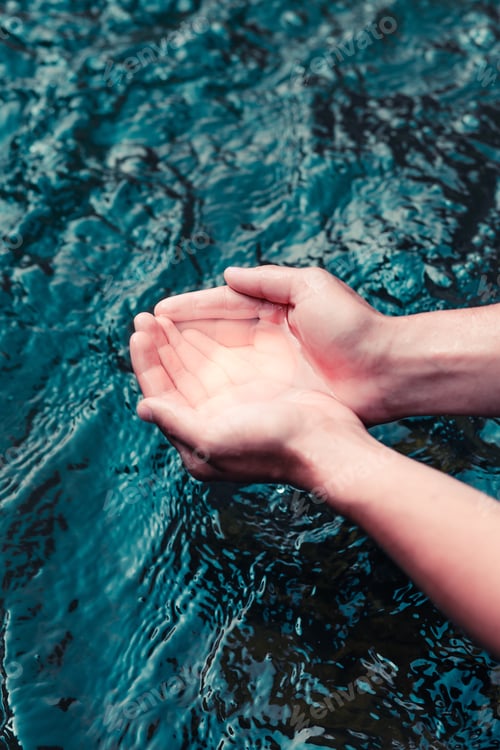Preview: Young boy taking pure water from river and holding it in the hands. Close to the nature. Clean water