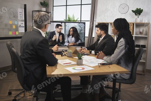 Preview: Focused business people in conference room, looking at a screen, having video conference