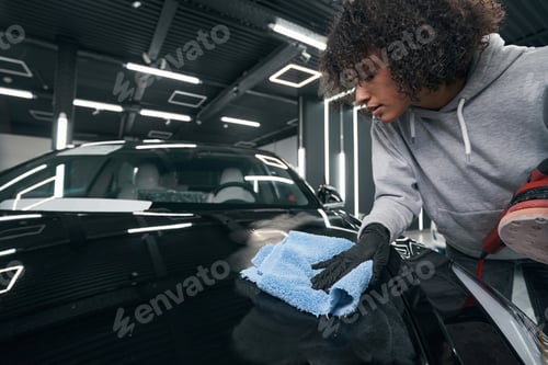 Preview: Focused skilled worker drying automobile exterior with clot