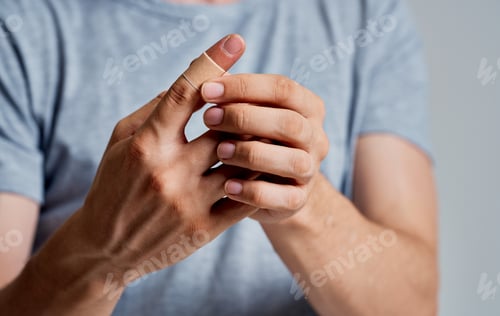 Preview: bactericidal plaster on the finger of a man in a t-shirt on a gray background