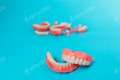 Preview: Dentures on a blue background. Close-up of dentures. Full removable plastic denture of the jaws