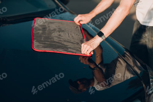 Preview: Worker washing car at car wash and wipes vehicle with rag.