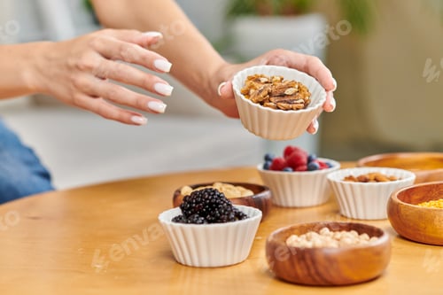 Preview: partial view of woman with bowl of walnuts near blackberries and assortment of plant-based food