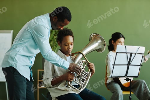 Preview: Young confident African American teacher of music consulting schoolboy