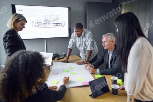 Preview: Architects discussing blueprint in office