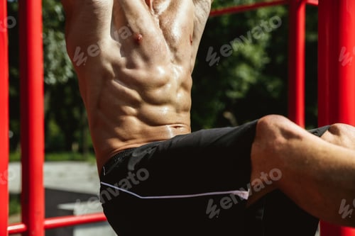 Preview: Young muscular man while doing his workout outside at playground
