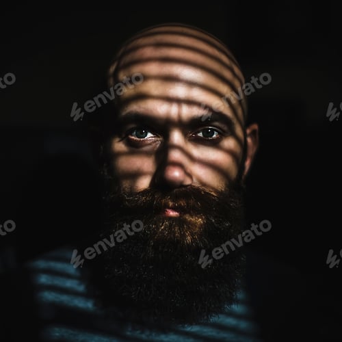 Preview: Close-up portrait of middle aged brutal bearded man with expressive eyes and striped shadows on face