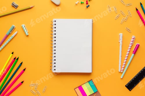 Preview: Back to school concept with a blank notebook and some stationery objects on a yellow background