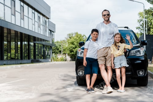 Preview: happy father in sunglasses standing near car with kids