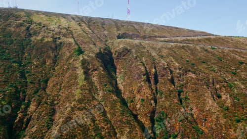 Preview: Drone volcanic mountain hills in summer. 5G telecommunication tower on top.
