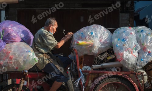 Preview: Asian elderly junk buyer carrying recycling waste onto 3 wheel motorbike on the street