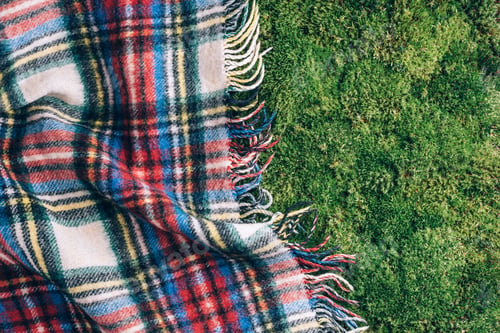 Preview: Checkered picnic plaid on green grass background. Top view. Copy space. Summer picnic time