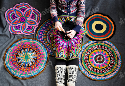 Preview: Neck down view of woman sitting on floor crocheting, surrounded by crochet circles