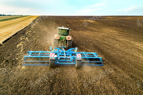 Preview: Aerial view of a tractor plowing black agriculture farm field after harvesting in late autumn.